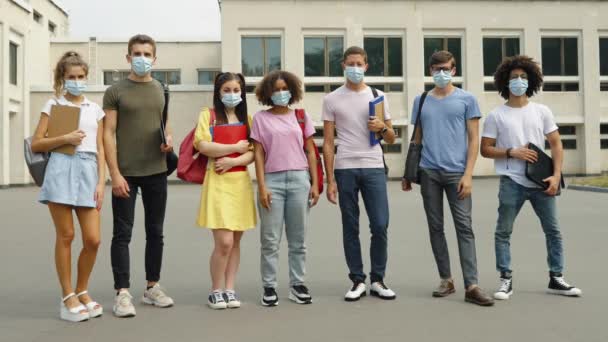 Estudiantes en máscaras contra edificio universitario — Vídeo de stock
