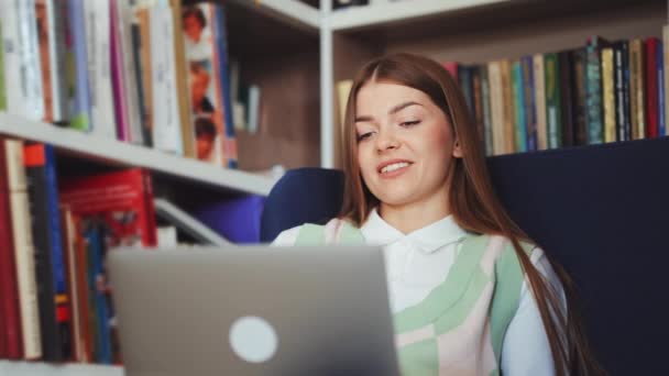 Mulher vídeo conversando via laptop na biblioteca — Vídeo de Stock