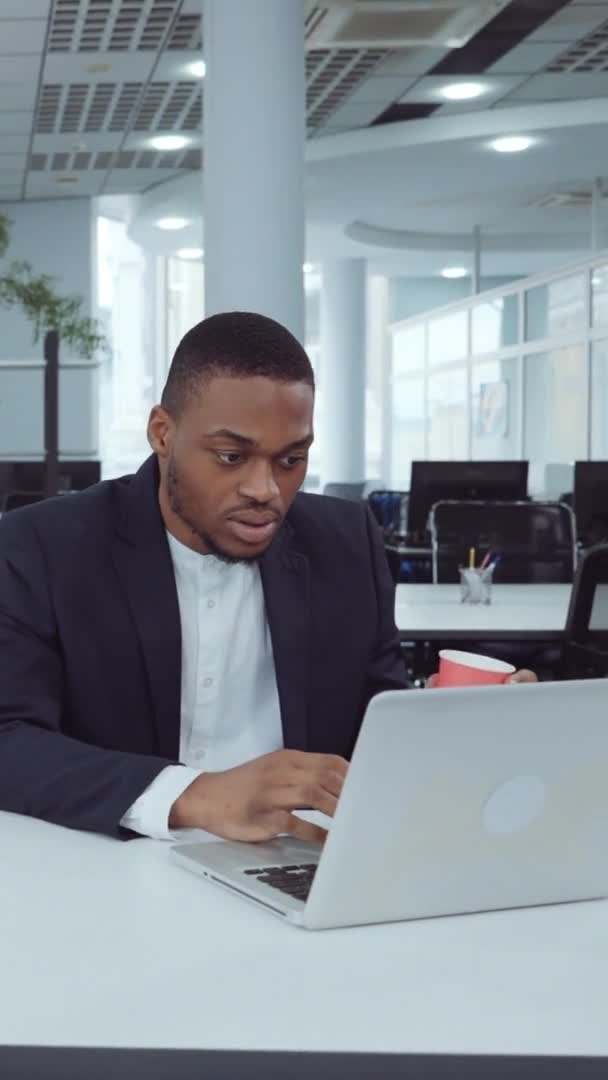 Pantalla vertical: hombre de negocios afroamericano usando el ordenador portátil en la oficina del espacio abierto — Vídeo de stock