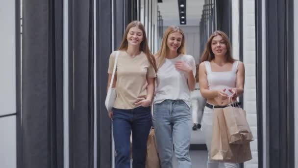 Счастливые женщины с покупками, проходящие мимо гримерки — стоковое видео