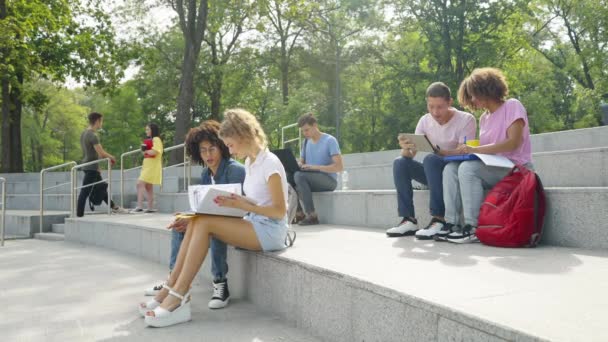 Diversos estudiantes sentados en escaleras en el campus — Vídeos de Stock