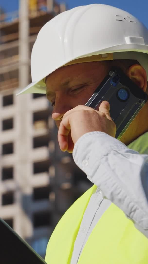 Ekran pionowy: Inżynier budowlany przeprowadzający inspekcję na placu budowy — Wideo stockowe