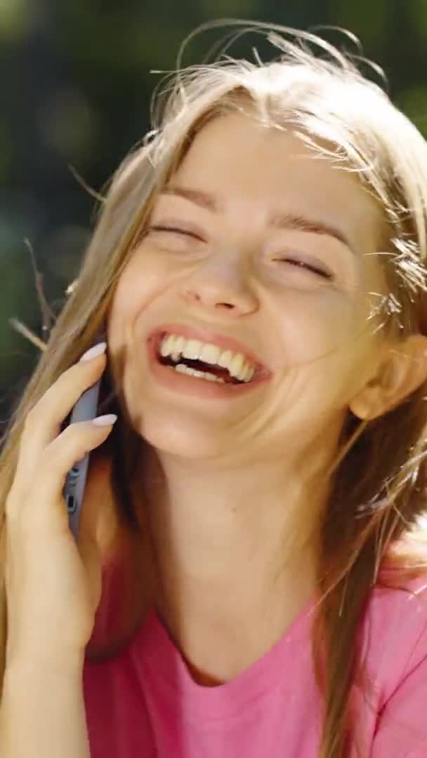 Dikey Ekran: Sarışın kadın telefonda konuşuyor ve gülüyor — Stok video