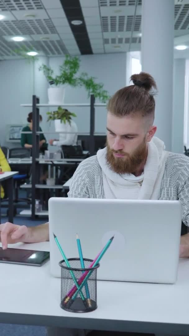 Écran vertical : Homme d'affaires Hipster utilisant un ordinateur portable et une tablette au bureau — Video