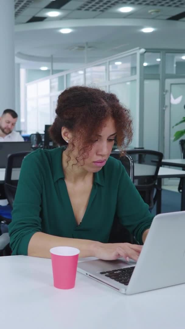 Écran vertical : Employée afro-américaine utilisant un ordinateur portable au bureau — Video