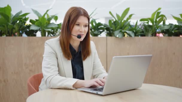 Call center manager talking on headset and using laptop — Stok Video