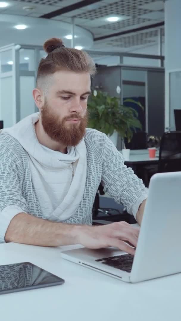 Ekran pionowy: hipsterski pracownik pracujący na laptopie w biurze — Wideo stockowe