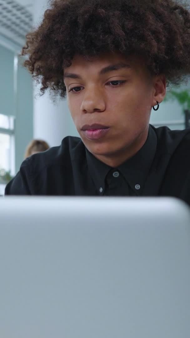 垂直:オープンスペースオフィスのラップトップ経由でビデオ通話を持つ黒人従業員 — ストック動画
