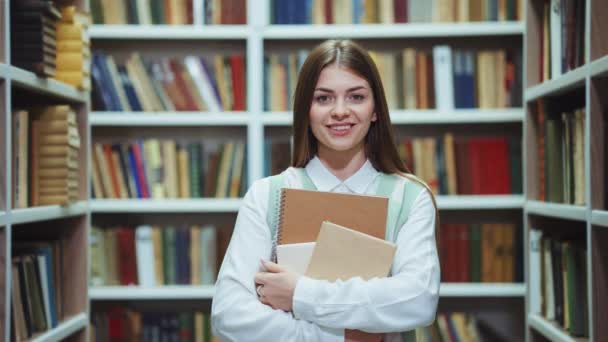 Cheerful student holding books in library — Video Stock