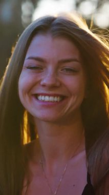 Dikey Ekran: Gün batımında kameraya gülen kadın