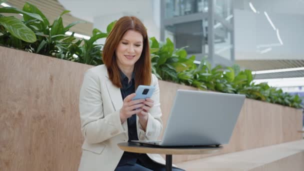 Glückliche Geschäftsfrau schreibt SMS auf Smartphone im Café — Stockvideo