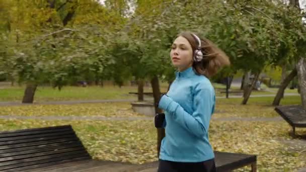 スローモーションで公園で実行されているヘッドフォンとジョギング — ストック動画
