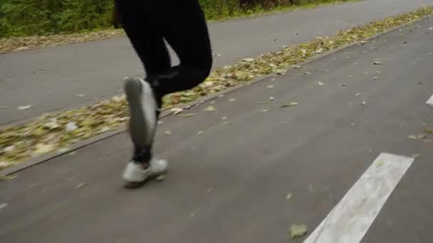 Pernas de corredor na estrada com folhas caídas — Vídeo de Stock