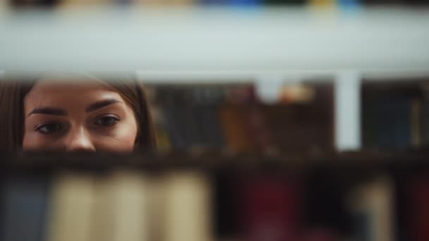 Estudante em busca de livro nas prateleiras da biblioteca — Vídeo de Stock