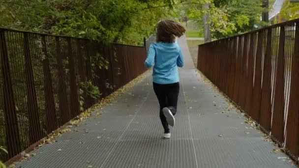 Вмістити жінку бігати по мосту в повільному русі — стокове відео