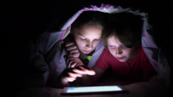 Enfants jouant jeu sur tablette la nuit sous couverture — Video