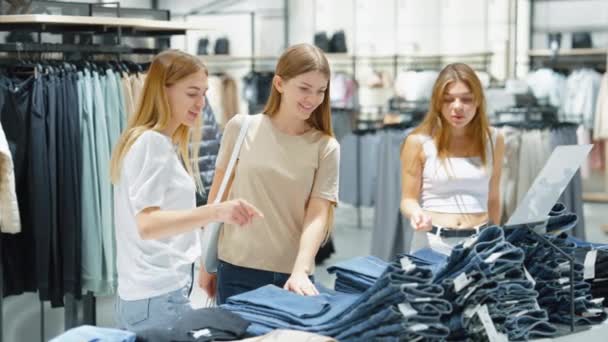 Mujeres comprando juntas comprando jeans en la tienda de ropa — Vídeos de Stock