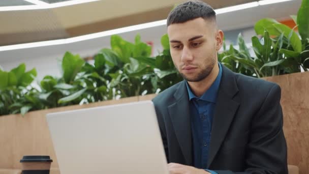 Молодой бизнесмен работает на ноутбуке в кафе — стоковое видео