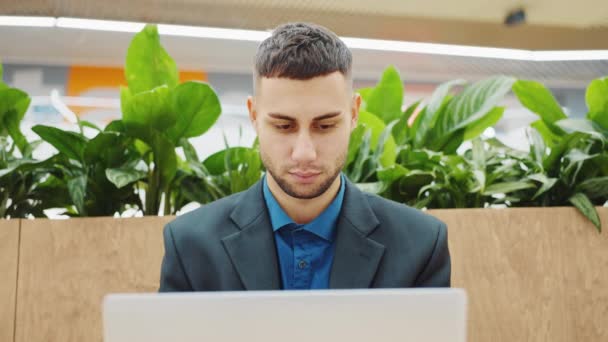 Jovem empreendedor trabalhando no laptop e sorrindo para a câmera — Vídeo de Stock