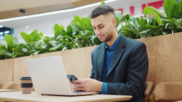 Empresário mensagens de texto no telefone enquanto trabalhava remotamente no café — Vídeo de Stock