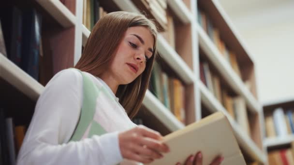 Mujer leyendo libro en la biblioteca — Vídeos de Stock