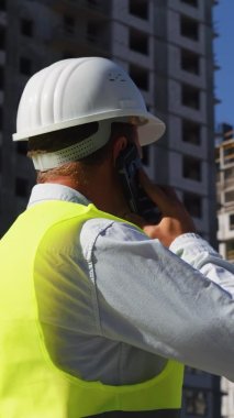 Dikey Ekran: İnşaat mühendisi inşaat alanında telefonla konuşuyor