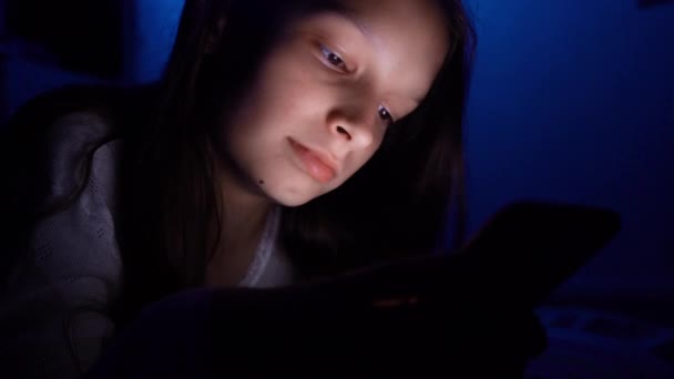 어둠 속에서 스마트폰을 쓰고 있는 예쁜 소녀 — 비디오