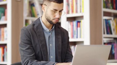 Adam kütüphanede bilimsel araştırma için internette geziniyor.