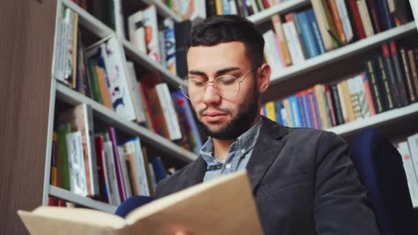 Homem inteligente lendo livro na livraria — Vídeo de Stock