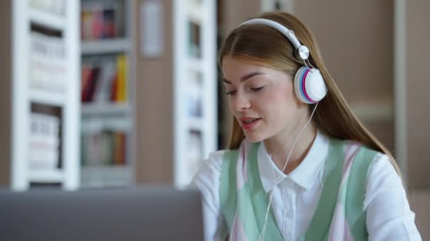 Estudante fazendo lição de casa no laptop e ouvindo música com fones de ouvido — Vídeo de Stock