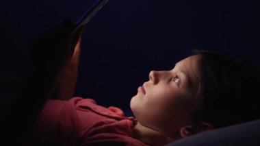 Kız gece tablette video izleyip şarkı söylüyor.