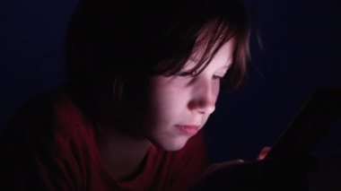 Küçük kız gece aletle video izliyor.