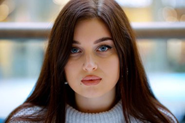 Uzun saçlı güzel bir kadın kameraya bakıyor.