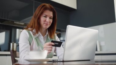 Yetişkin bir kadın internetten alışveriş için kredi kartı kullanıyor.