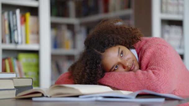 Κουρασμένος μαθητής ξαπλωμένος σε βιβλία στη βιβλιοθήκη — Αρχείο Βίντεο