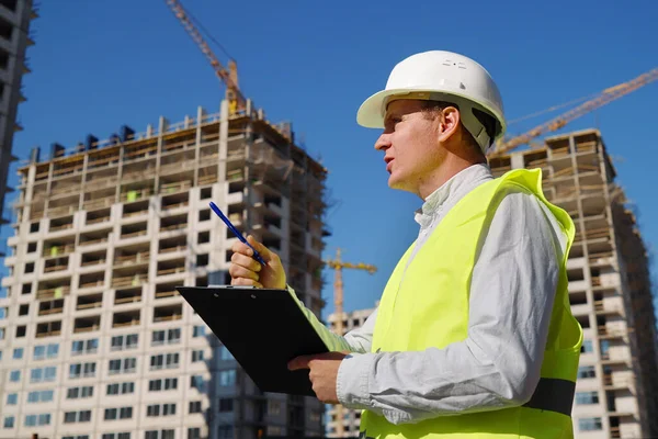 İnşaat müfettişi inşaat alanında notlar alıyor.