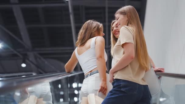 Mujeres de pie en la escalera móvil en el centro comercial — Vídeos de Stock