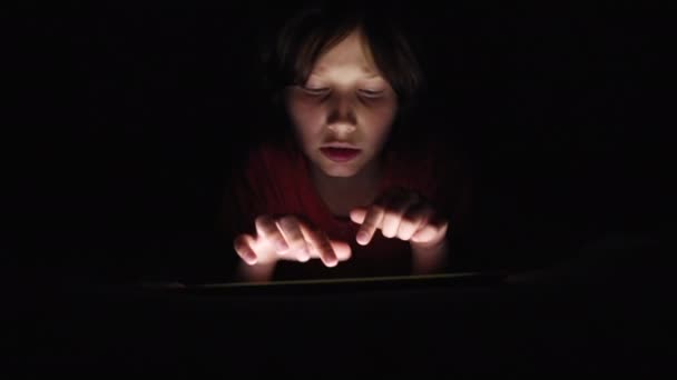 Παιδί παίζει το παιχνίδι στο tablet τη νύχτα — Αρχείο Βίντεο