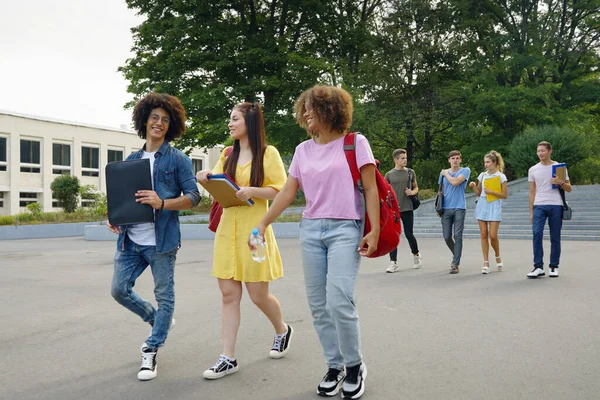 Kampüste kitap ve sırt çantalı öğrenciler yürüyor.