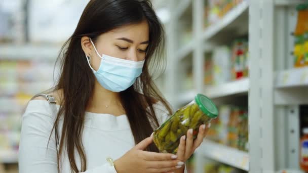 Azjatka czyta etykietę na ogórkach w sklepie — Wideo stockowe