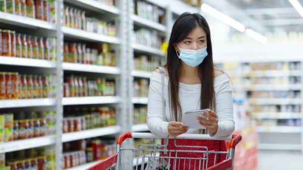 Customer in mask choosing food according to shopping list — Stock Video