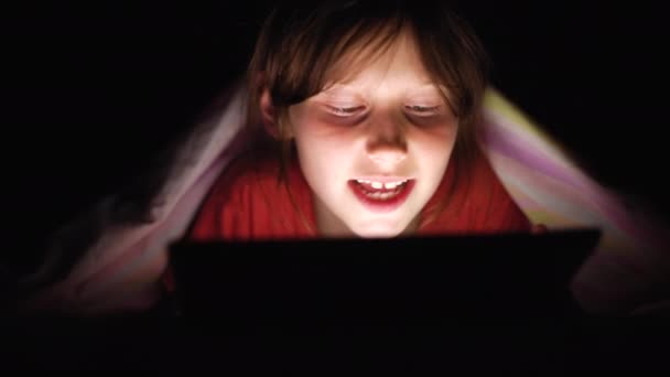 Dítě ležící pod dekou a užívající v noci tabletu — Stock video