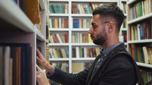 Studenten op zoek naar boeken in de bibliotheek — Stockvideo