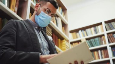 Maskeli adam kitapçıda kitap okuyor.