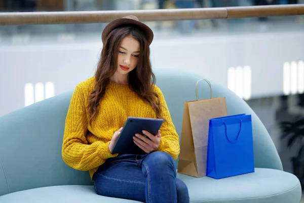 Young woman reading e-book in shopping mall — Stock Photo, Image