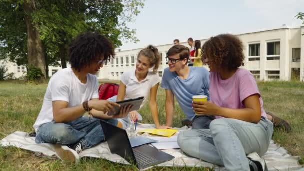 Студенти відпочивають на траві в кампусі — стокове відео