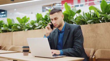 Kafede çalışan ve telefonla konuşan bir iş adamı.