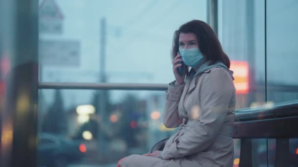 Kvinna i mask pratar i telefon i staden — Stockvideo