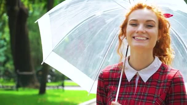 Vörös hajú nő sétál esernyővel a napon — Stock videók