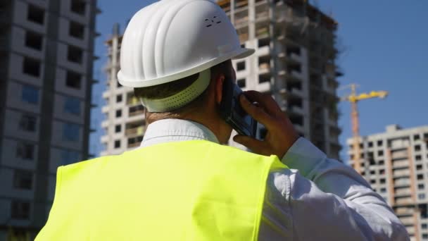 Будівельний інспектор на будівельному майданчику розмовляє по телефону — стокове відео